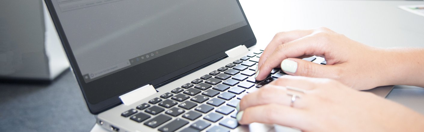 Hände die auf einer Laptoptastatur tippen